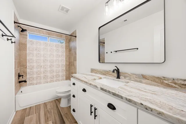 a bathroom with a granite countertop sink a toilet a mirror and shower