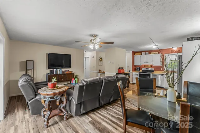 a living room with furniture a flat screen tv and kitchen view