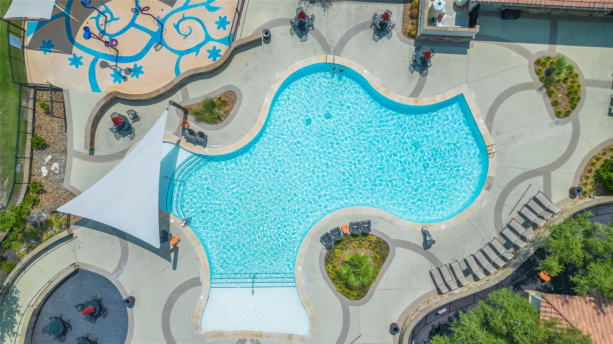 1128 Villa Rialto View Leander, TX 78641 - Photo 38 of 40 An aerial perspective showcases a vibrant community pool with inviting lounging areas and an adjacent splash pad.