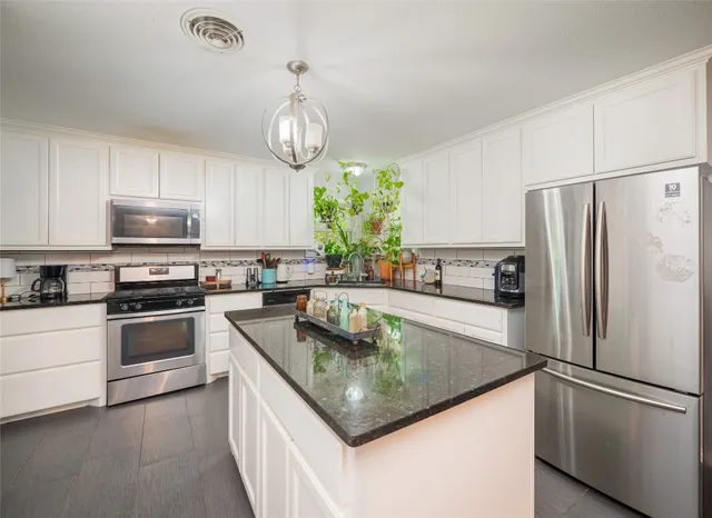 a kitchen with granite countertop stainless steel appliances a refrigerator a stove cabinets and a sink