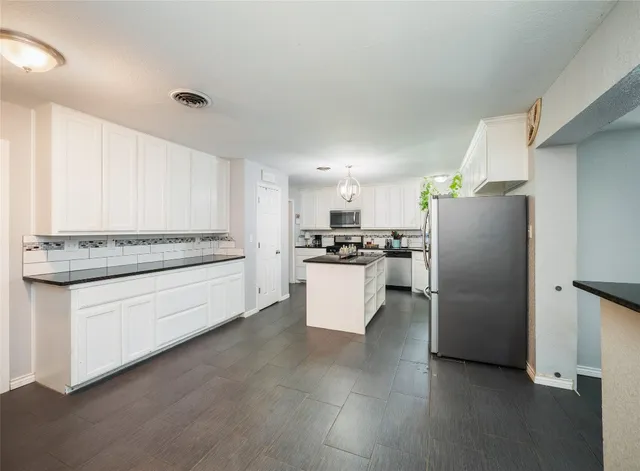 a kitchen with stainless steel appliances granite countertop a refrigerator sink and white cabinets