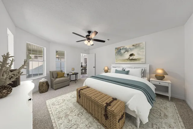 a spacious bedroom with a bed a couch and potted plant on the dresser