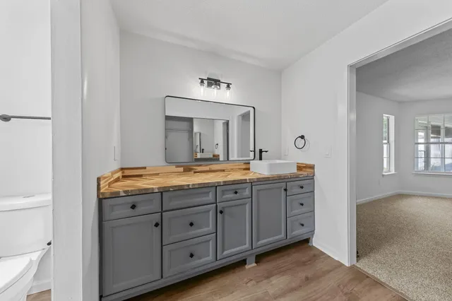 a bathroom with a granite countertop sink mirror and toilet