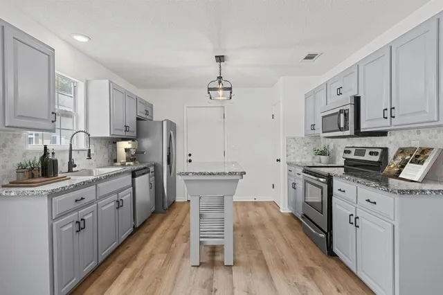 a kitchen with stainless steel appliances granite countertop a sink stove and refrigerator