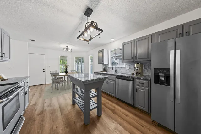a kitchen with stainless steel appliances a kitchen island hardwood floor sink stove dining table and chairs