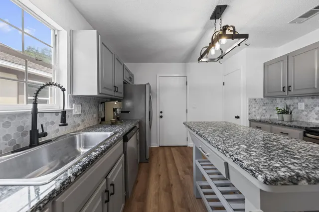 a kitchen with stainless steel appliances granite countertop a sink stove and refrigerator