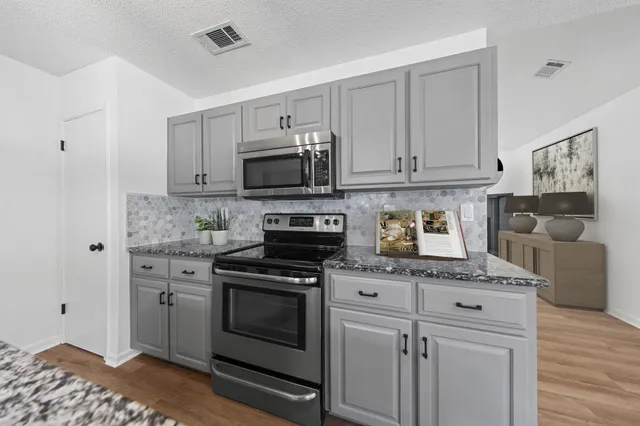a kitchen with granite countertop a stove top oven microwave and cabinets