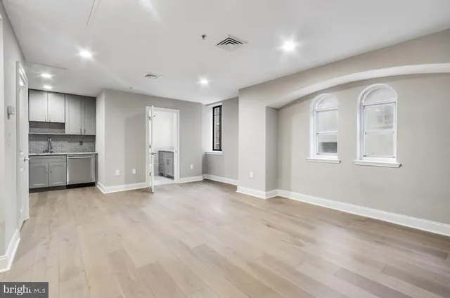 a view of empty room with kitchen and window