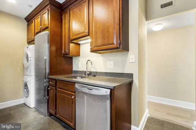 a view of a kitchen with kitchen island a sink wooden floor and a refrigerator