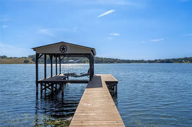 a kitchen with stainless steel appliances granite countertop a refrigerator a stove a sink a dining table and chairs with wooden floor