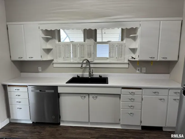 a kitchen with white cabinets and sink