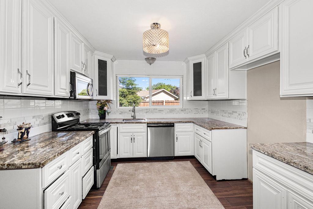 1124 Lakewood Avenue Modesto, CA 95355 - Photo 17 of 40 a kitchen with stainless steel appliances granite countertop a sink and dishwasher a stove top oven with wooden floor