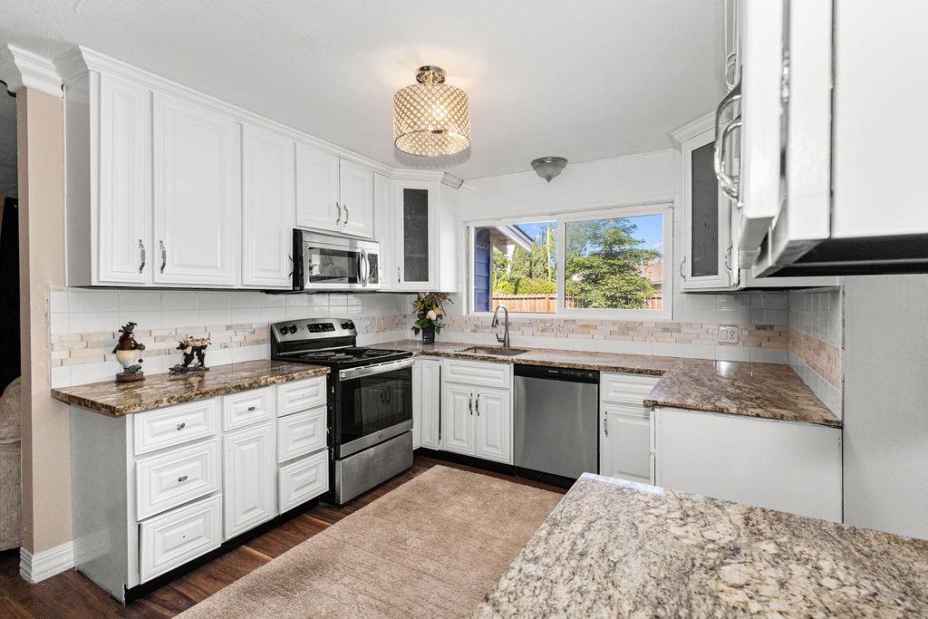 1124 Lakewood Avenue Modesto, CA 95355 - Photo 18 of 40 a kitchen with stainless steel appliances granite countertop a stove a sink dishwasher and a microwave oven with white cabinets