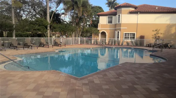 a view of swimming pool with a patio and palm trees