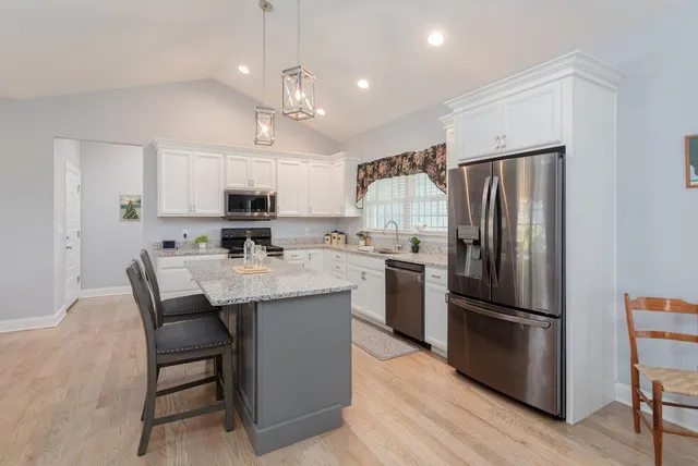 a kitchen with stainless steel appliances granite countertop a sink stove refrigerator and cabinets