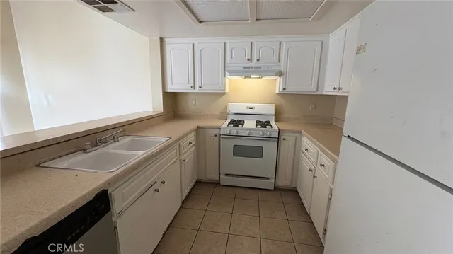 a kitchen with granite countertop a sink stove top oven and cabinets