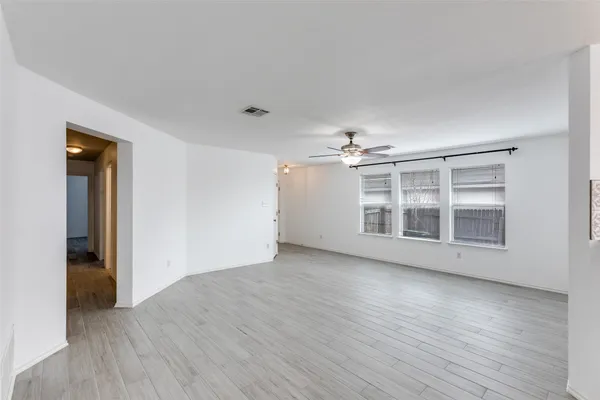 a view of empty room with wooden floor and windows