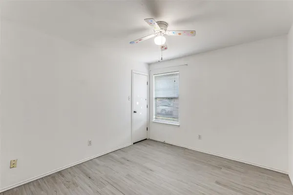 an empty room with a chandelier fan and windows