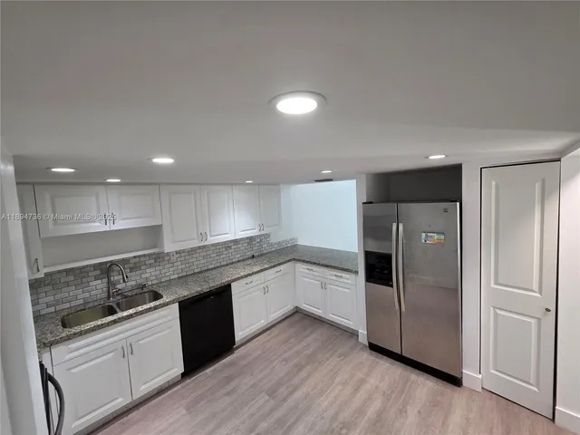 a kitchen with a refrigerator and white cabinets