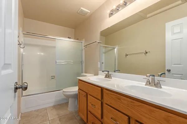 a bathroom with a double vanity sink toilet mirror and shower