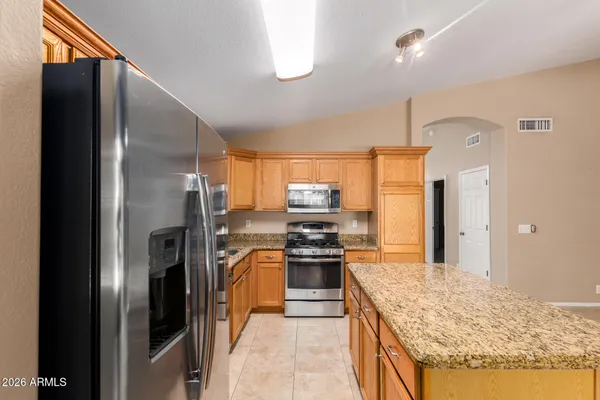 a kitchen with stainless steel appliances granite countertop a refrigerator a stove and a sink