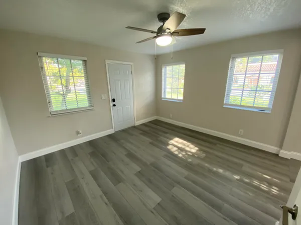 an empty room with wooden floor and windows