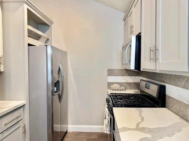 a kitchen with granite countertop a sink a stove and cabinets