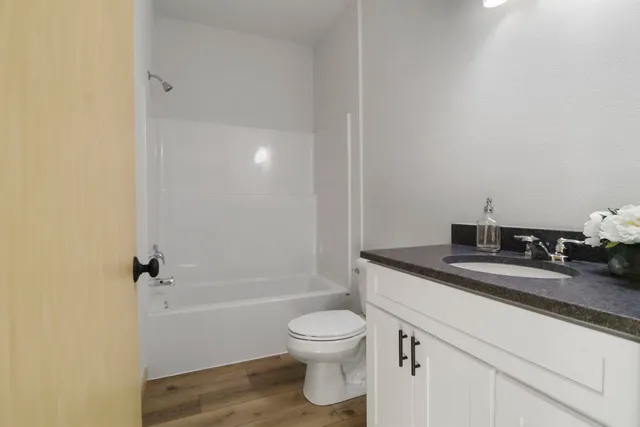 a bathroom with a granite countertop sink a toilet and shower