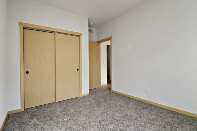a view of an empty room with closet and a window