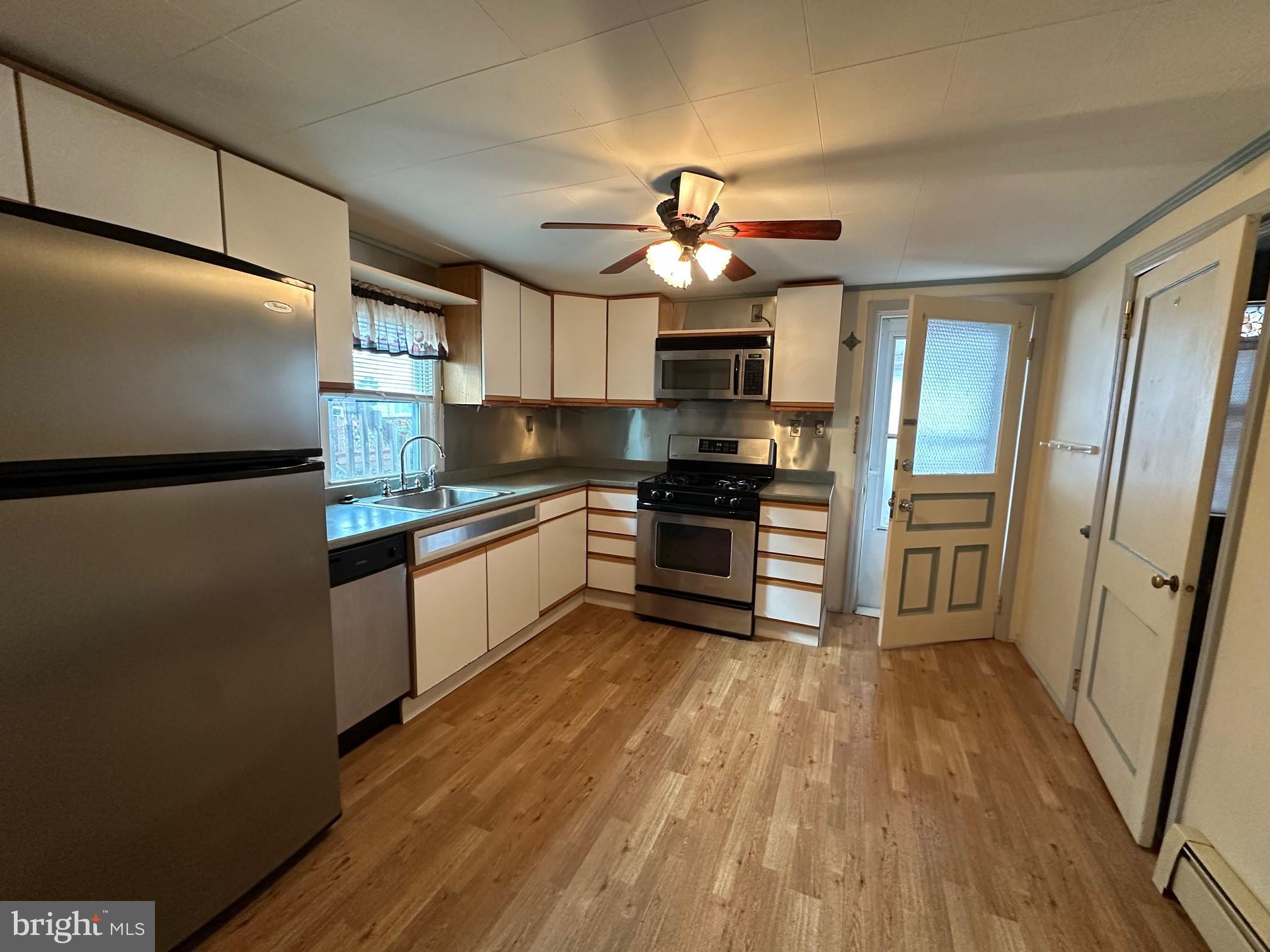 308 A Ash Street Delanco, NJ 08075 - Photo 2 of 11 a kitchen with stainless steel appliances a refrigerator a sink dishwasher a stove and white cabinets with wooden floor