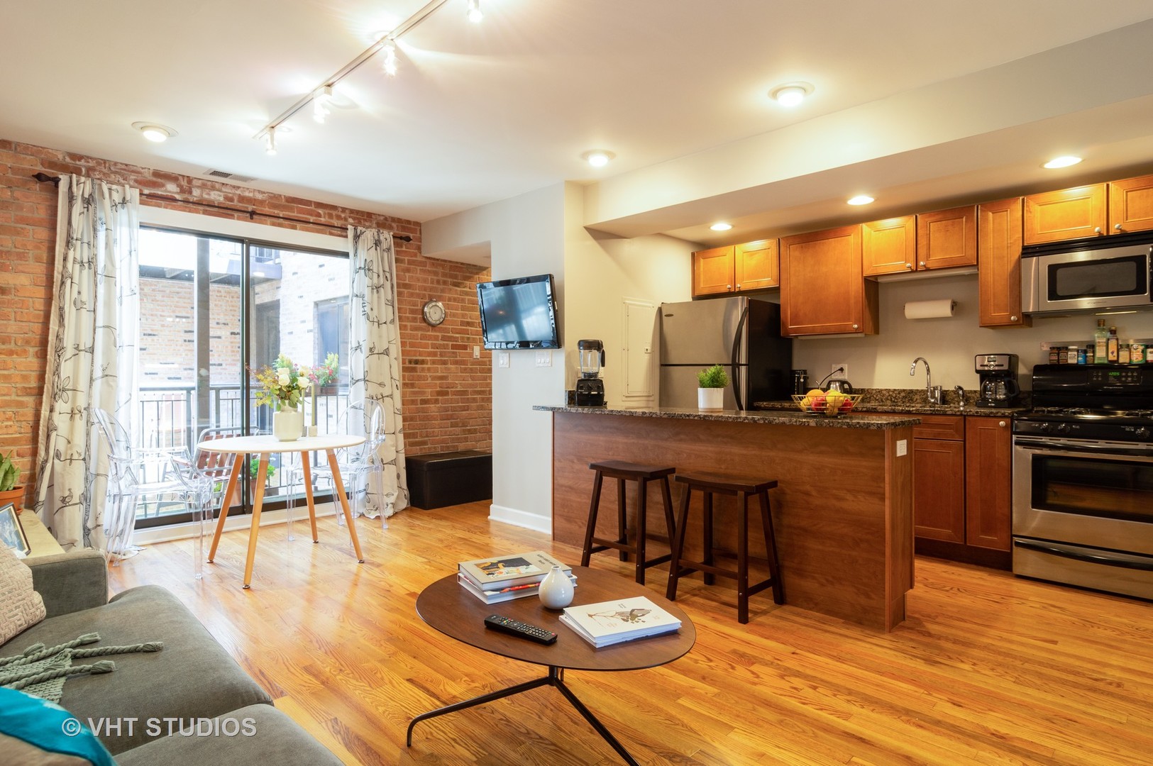 711 West Melrose Street, Unit B2 Chicago, IL 60657 - Photo 8 of 22 a kitchen with stainless steel appliances granite countertop a stove a refrigerator a couch and a dining table with wooden floor