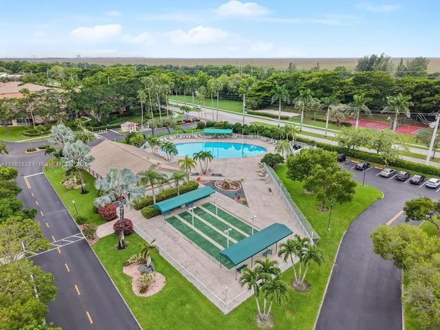 a view of a swimming pool that has lawn chairs with plants and palm trees