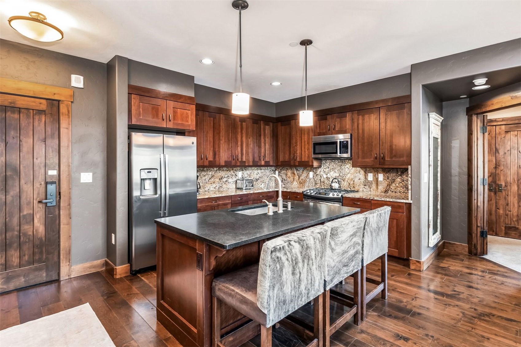 600 Columbine Road, Unit 5305 Breckenridge, CO 80424 - Photo 6 of 36 a kitchen with stainless steel appliances granite countertop a kitchen island a stove a refrigerator a sink a dining table and chairs with wooden floor