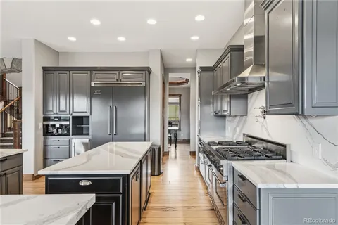 a dining room with stainless steel appliances granite countertop a refrigerator a stove a dining table and chairs with wooden floor