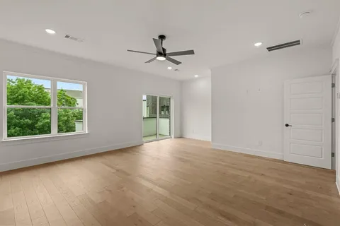 an empty room with wooden floor chandelier fan and windows
