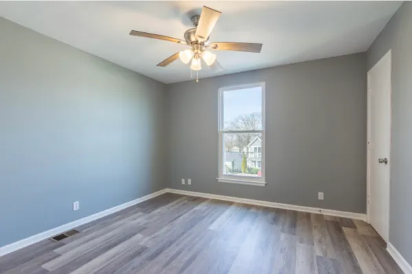 an empty room with wooden floor and windows