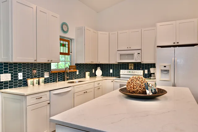 a kitchen with a sink a stove and white cabinets