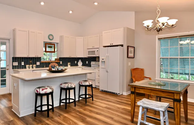 a kitchen with stainless steel appliances granite countertop a stove a refrigerator a sink a dining table and chairs with wooden floor