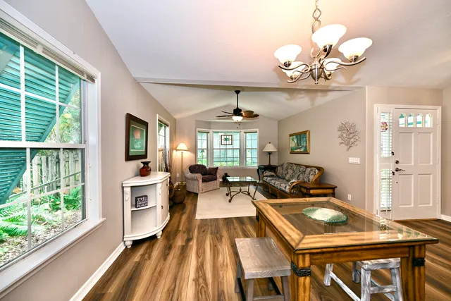 a view of a dining room with furniture a chandelier and large windows