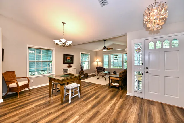a living room with furniture a chandelier and a dining table with wooden floor