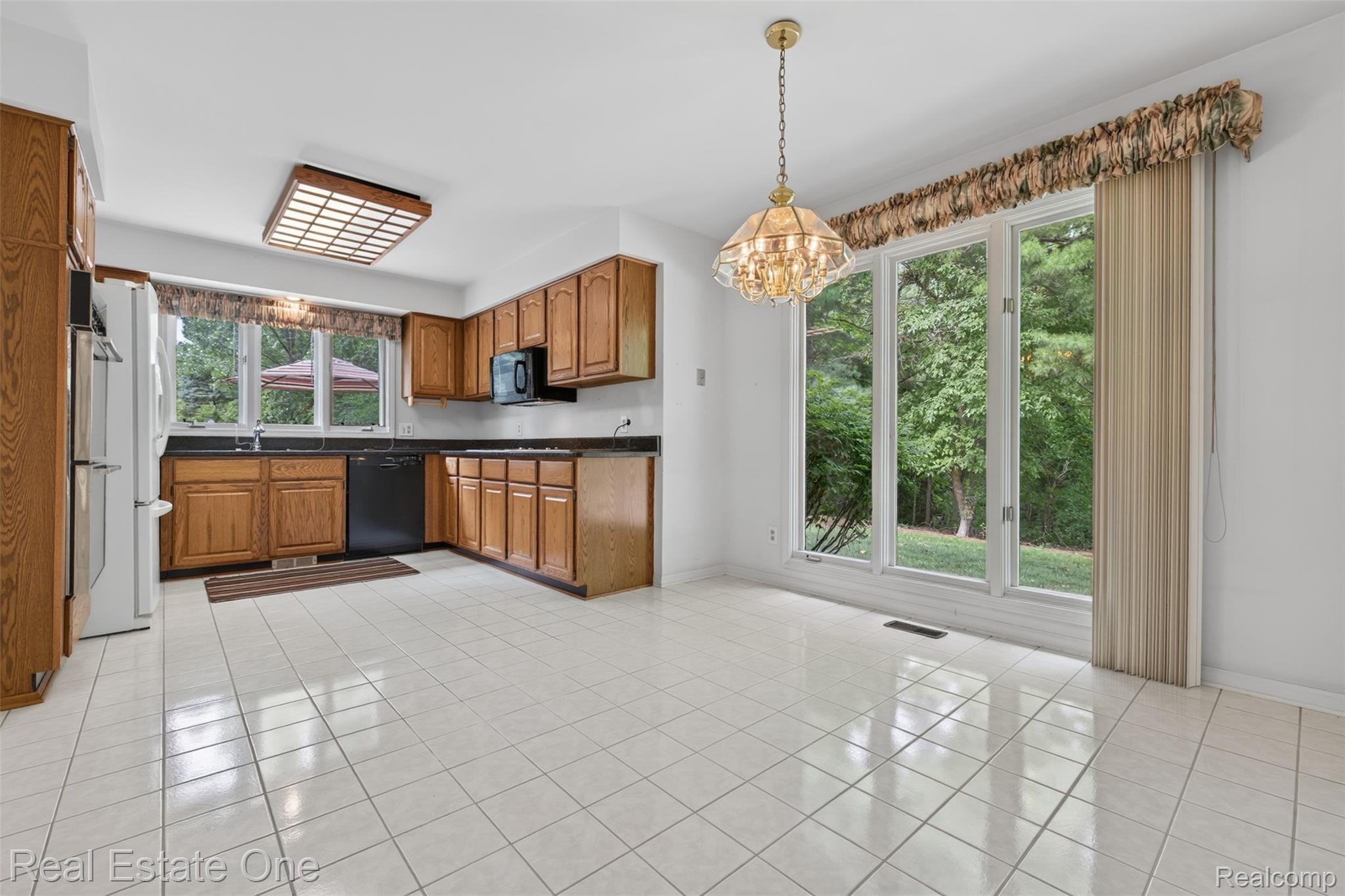 3400 Wedgewood Drive Rochester, MI 48306 - Photo 14 of 49 Eat-in kitchen featuring white tile flooring, wood cabinetry, dark countertops, and a full suite of appliances