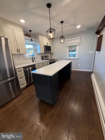 a kitchen with kitchen island a sink counter top space stainless steel appliances and a window