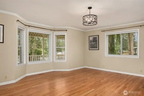 a big room with wooden floor a chandelier and windows