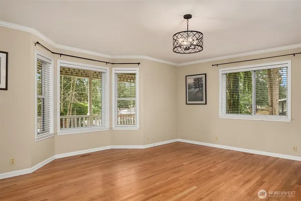 a big room with wooden floor a chandelier and windows