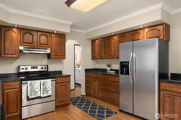 a kitchen with stainless steel appliances granite countertop a refrigerator a stove and a sink with cabinets