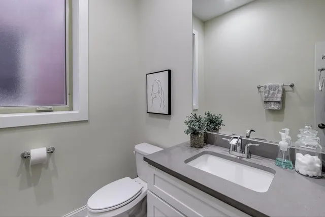 a bathroom with a granite countertop sink mirror vanity and toilet