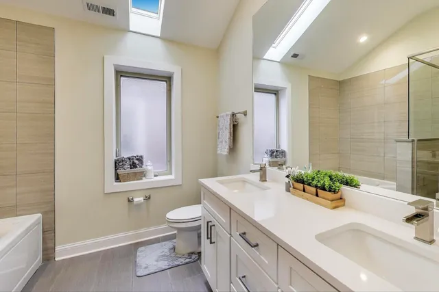 a bathroom with a double vanity sink toilet and a tub