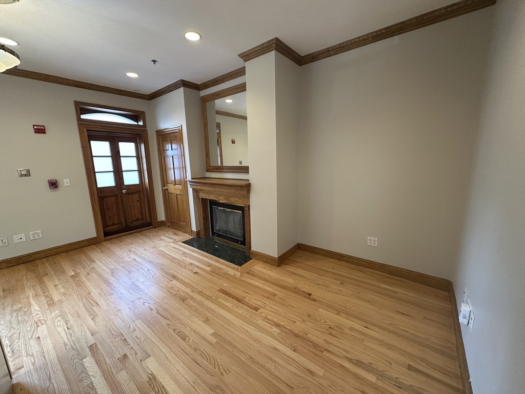 57 Gainsborough Street, Unit 2 Boston, MA 02115 - Photo 4 of 8 a view of empty room with wooden floor and fireplace