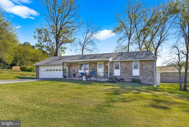 a view of a house with a big yard and large trees