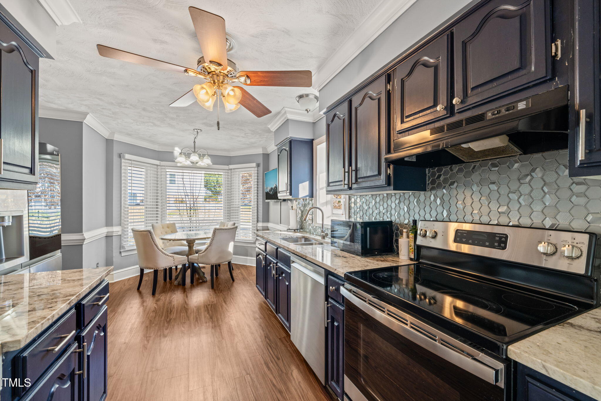 3701 East Jameson Road Raleigh, NC 27604 - Photo 9 of 26 a kitchen with stainless steel appliances granite countertop hardwood floor sink stove dining table and chairs